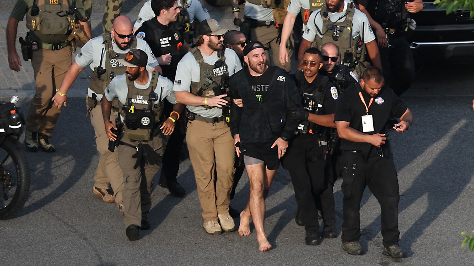 https://images.bfmtv.com/Y746Dm5SacWBwmP8u8Ozst8rw94=/11x183:1819x1200/images/Sean-Strickland-escorte-par-la-police-apres-s-etre-invite-a-la-fan-fest-de-l-UFC-Maison-Blanche-le-14-juin-2026-2303708.jpg