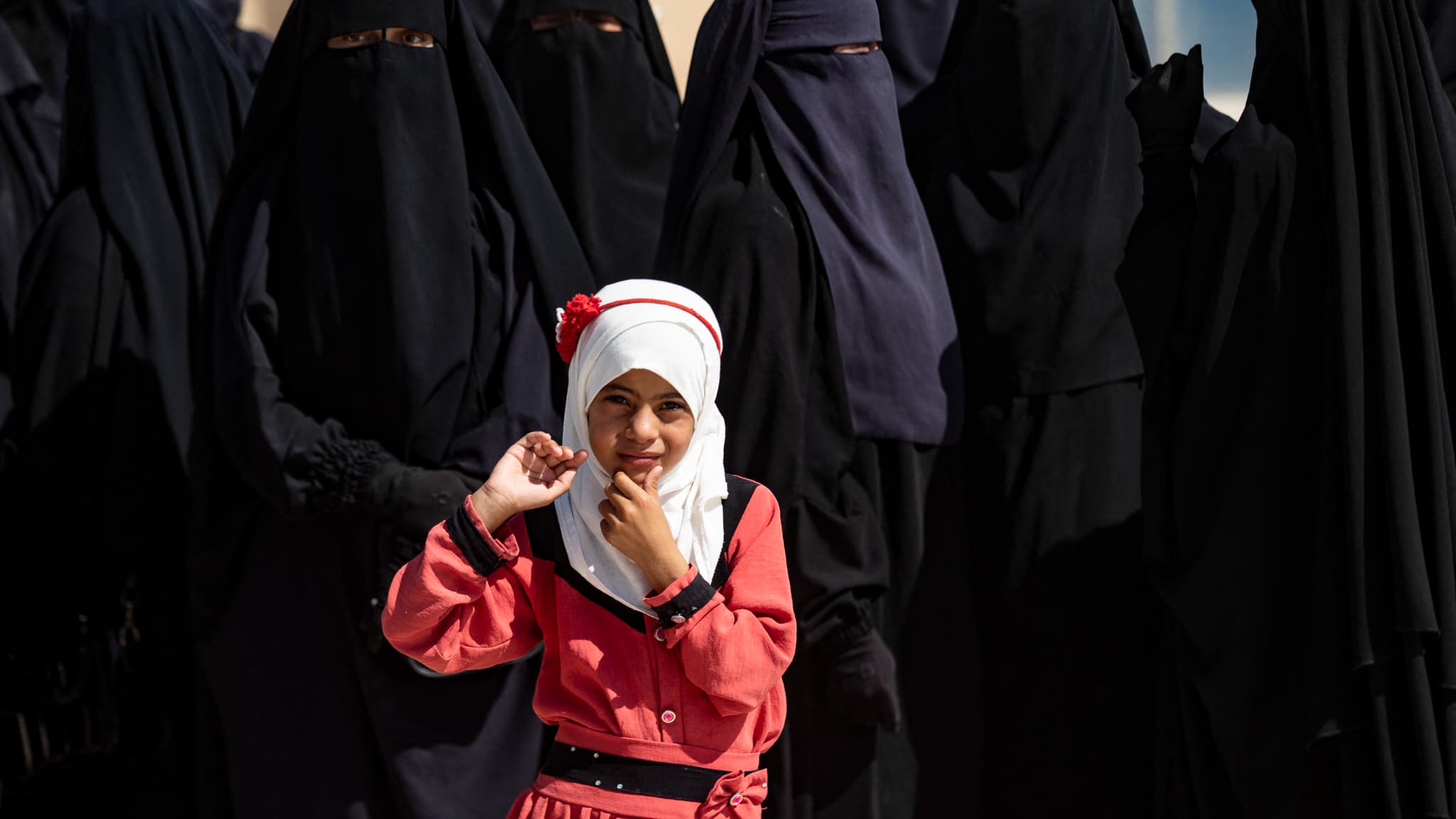 Une fillette observe des ressortissants irakiens qui se préparent à quitter le camp d'al-Hol, géré par les Kurdes, dans le gouvernorat d'al-Hasakah, au nord-est de la Syrie, avant leur retour en Irak le 28 août 2025. 