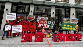 Des militants du collectif Stop Total protestent contre le financement d'un projet controversé d'exploitation de combustibles fossiles en Afrique, devant les bureaux français de la banque japonaise Sumitomo Mitsui Banking Corporation et de la banque britannique Standard Chartered Bank, dans le quartier du 8e arrondissement de Paris, le 22 février 2023.