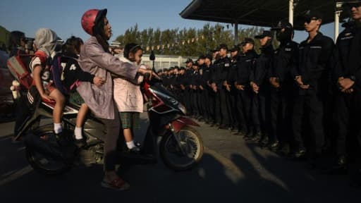 Une femme qui emmène ses enfants à l'école, est bloquée par des policiers devant le temple de Dhammakaya, le 16 février 2017 au nord de Bangkok, en Thaïlande Une femme qui emmène ses enfants à l'école, est bloquée par des policiers devant le temple de Dhammakaya, le 16 février 2017 au nord de Bangkok, en Thaïlande