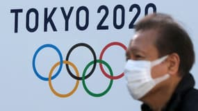 Un homme portant un masque passe devant le logo des Jeux olympiques de Tokyo le 4 février 2021