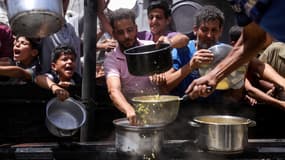 Des Palestiniens déplacés se rassemblent pour récupérer des portions de nourriture cuite lors d'une distribution caritative à Jabalia, dans le nord de la bande de Gaza, le 19 mai 2025.