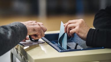 Une personne dépose un bulletin de vote lors des élections parlementaires européennes, dans un bureau de vote. 