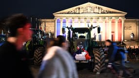 Un piéton passe devant des tracteurs garés devant l'Assemblée nationale à Paris le 13 janvier 2026.