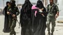 Des gardes escortent des femmes, vraisemblablement des compagnes de combattants du groupe Etat islamique dans le camp d'al-Hol, en Syrie, le 23 juillet 2019