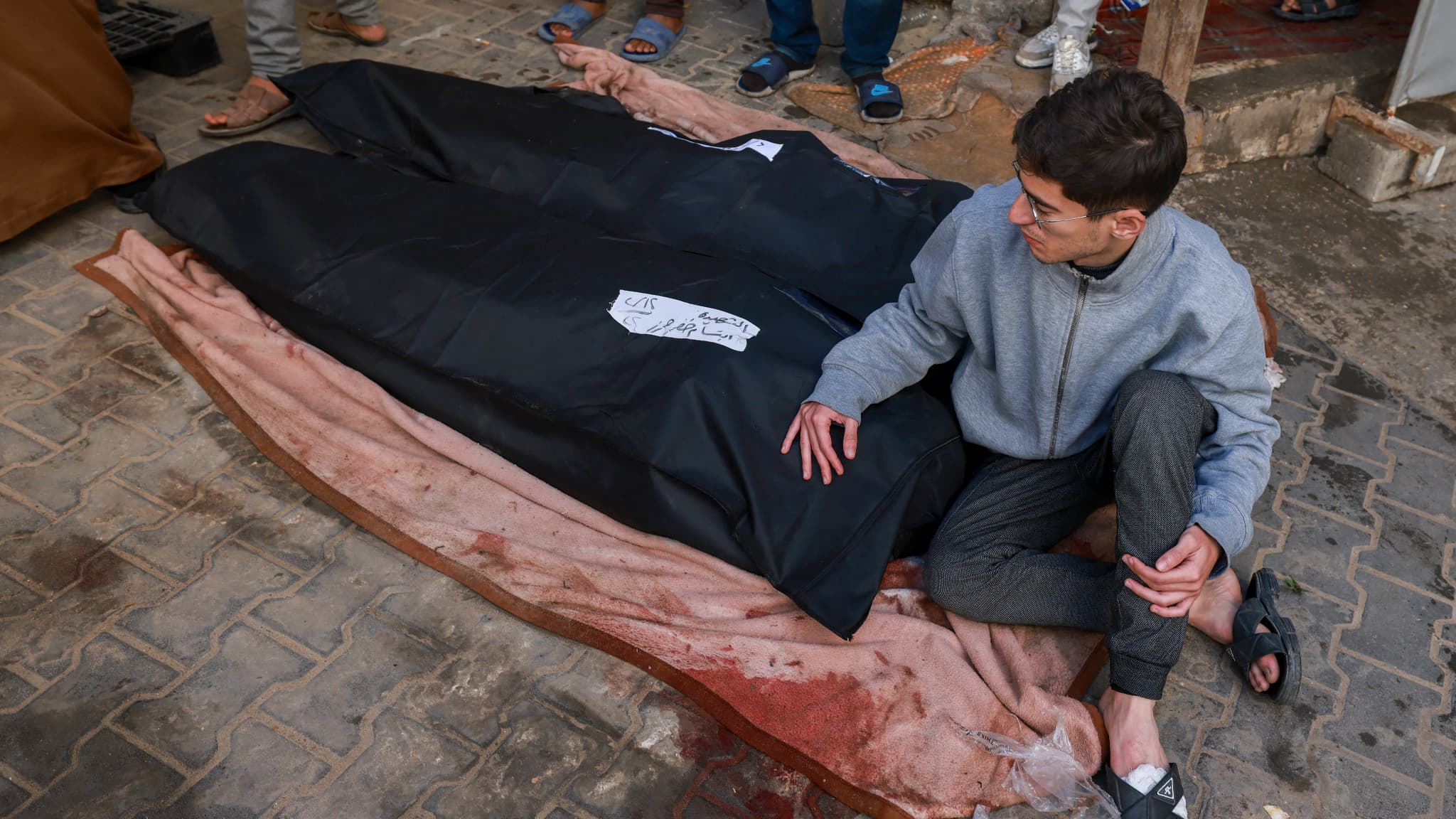 Un homme est assis à côté des corps de proches tués lors d'un bombardement israélien, à l'hôpital Al-Najar de Rafah, dans le sud de la bande de Gaza, le 12 février 2024.