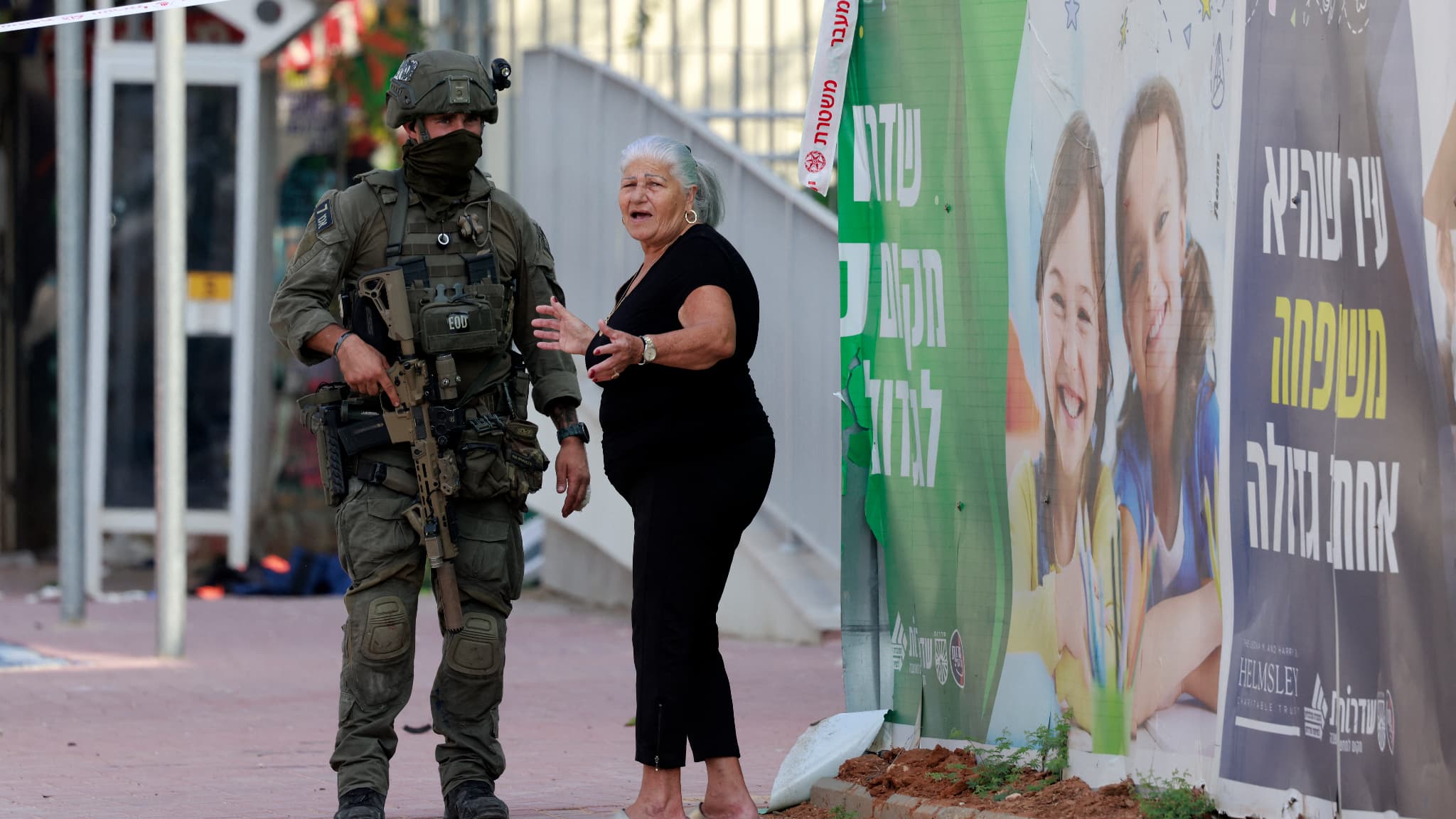 Une résidente se tient avec un soldat israélien près d'un poste de police israélien bouclé qui a été endommagé lors des batailles pour déloger les militants du Hamas qui étaient stationnés à l'intérieur, le 8 octobre 2023. Une résidente se tient avec un soldat israélien près d'un poste de police israélien bouclé qui a été endommagé lors des batailles pour déloger les militants du Hamas qui étaient stationnés à l'intérieur, le 8 octobre 2023.