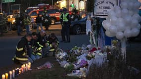 Des pompiers se recueillent près de l'école primaire Sandy Hook, à Newtown, dans le Connecticut. Barack Obama doit se rendre ce dimanche à Newtown pour y rencontrer les familles des victimes de la tuerie survenue vendredi dans l'école primaire de cette vi