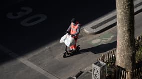 Un homme porte des sacs de courses sur une trottinette électrique, le 6 avril à Paris.
