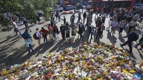 Des piétons s'arrêtent pour observer les fleurs déposées en mémoire des victimes de l'attaque terroriste du 3 juin à Londres (Royaume-Uni), le 9 juin 2017. 