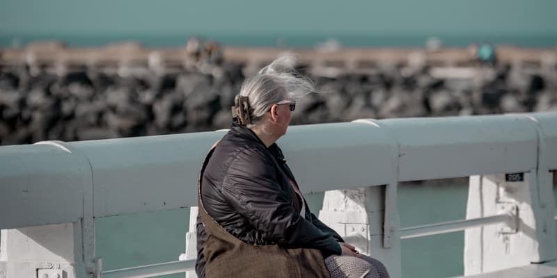Une femme âgée assise sur un ponton. Photo d'illustration