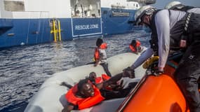 Un sauveteur de Médecins sans frontière venant en aide à un homme dans un bateau gonflable en Méditerranée en juin 2022