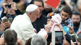 Le pape François salue un bébé pendant l'audience générale au Vatican le 18 novembre 2015