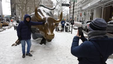 Un touriste pose devant la statue du taureau de Wall Street dans un froid extrême à New York, aux États-Unis, le 27 janvier 2026.