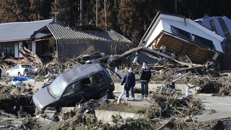 Des piétons se tiennent à côté de maisons effondrées après avoir été frappés par un tsunami à Minamisoma, préfecture de Fukushima, le 12 mars 2011. (Photo d'illustration)