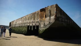 Des touristes devant le port artificiel à Arromanches