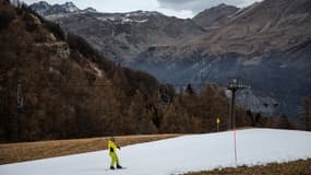 Un snowboardeur descend une piste de ski avec de la neige à canons à Sampeyre, dans le nord-ouest de l'Italie, le 2 janvier 2025. 