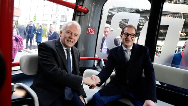 Le patron de la Deutsche Bahn, Ruediger Grube, et le ministre fédéral des Transports et des Infrastructures numériques, Alexander Dobrindt, se serrent la main dans un mini-bus autonome à Berlin.