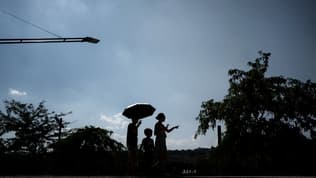 Une famille se promène avec un parapluie pour s'abriter du soleil à Lyon, le 21 août 2023.