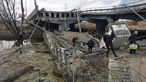 Des piétons traversent un pont détruit alors qu'ils évacuent la ville d'Irpine (Ukraine), au nord-ouest de Kiev, le 6 mars 2022