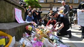 Des passants déposent des fleurs en hommage aux victimes de l'attentat, le 23 mai, dans le centre de Manchester. 