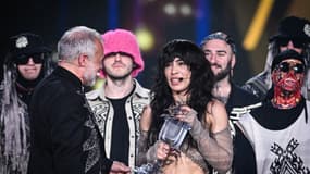 Loreen récupérant son trophée après avoir remporté l'Eurovision 2023 entourée des Kalush Orchestra, les gagnants de l'édition précédente 