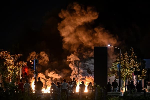 Un groupe de personnes regardent des pneus brûlés à Bordeaux lors d'une nuit d'émeutes le 29 juin 2023