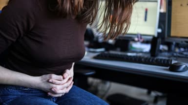 Une femme, assise à son bureau, souffre de douleurs menstruelles, le 1er mars 2023 à Toulouse