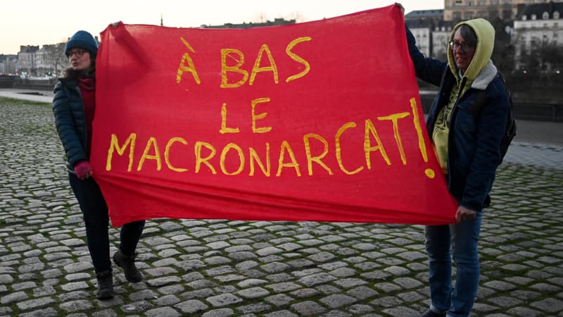 Des militantes féministes brandissent une banderole avec un jeu de mots entre le nom du président français Emmanuel Macron et le patriarcat pour lire « A bas la macronararchie » lors d'une manifestation contre le sexisme, devant le palais de justice de Nantes, dans l'ouest de la France, le 11 janvier 2024.
