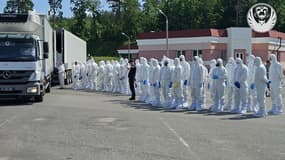 Le personnel du Comité international de la Croix-Rouge se tient à côté de camions frigorifiques lors de la restitution de corps rendus par la Russie, en Ukraine, le 16 juin 2025.
