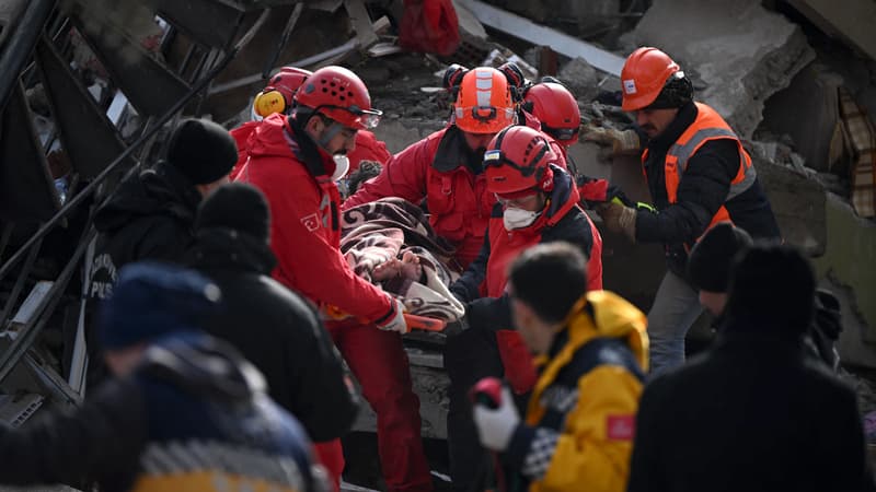 Des secouristes transportent un jeune homme secouru sur un brancard à travers les décombres des bâtiments de Kahramanmaras, l'épicentre du séisme en Turquie, le 7 février 2022.