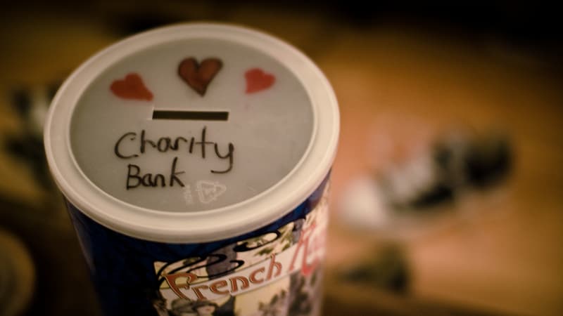 Une photographie de boite à sous avec une inscription "banque de la charité" sur le couvercle