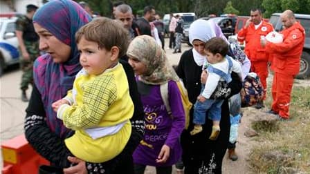 Des membres de la Croix-Rouge libanaise accueillent des civils ayant fui la Syrie à leur arrivée à Wadi Khaled, dans le nord du Liban. Des centaines de Syriens ont fui vers le Liban voisin alors que trois personnes ont trouvé la mort samedi lors de l'entr