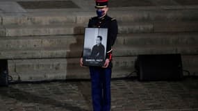 Un garde républicain porte le portrait de l'enseignant assassiné Samuel Paty lors de l'hommage national à la Sorbonne le 21 octobre 2020. 