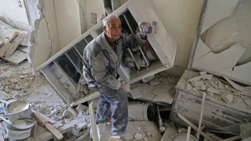 Un vieil homme syrien montre le 1er mars 2018 une photo de famille qu'il a trouvée dans les décombres de sa maison à Kafr Batna, dans l'enclave rebelle dans la Ghouta orientale, près de Damas, bombardée par les forces du régime