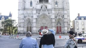 Des passants regardent la façade de la cathédrale Saint-Pierre-et-Saint-Paul de Nantes touchée par un incendie, le 19 juillet 2020