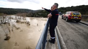 Des pompiers observent le Gardon en crue, à Russan, dans le Gard, le 10 mars 2024