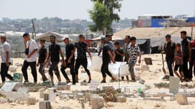 Des personnes portent le corps d'une personne après que des corps aient été déterrés de tombes temporaires à l'hôpital al-Amal de Khan Yunis, dans le sud de la bande de Gaza, le 18 juillet 2024. 
