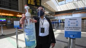 Un employé pose avec du gel hydroalcoolique dans l'aéroport international de Los Angeles, le 12 août 2020