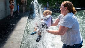 Une femme rafraîchit son enfant dans une fontaine de Washington D.C. (États-Unis), le 28 juin 2021.