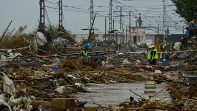 Des agents au milieu de débris sous la pluie à Paiporta, au sud de Valence, dans l'est de l'Espagne, le 13 novembre 2024, après les inondations.