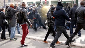 Le personnel de sécurité, avec des brassards orange, pulvérise du gaz lacrymogène alors qu'il est  submergé par des jeunes cagoulés et masqués, lors de manifestations le 13 novembre 2014, à Paris.