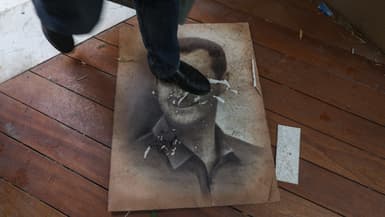 Un homme marche sur une photo du président syrien évincé Bachar el-Assad alors que des personnes entrent dans sa résidence dans le quartier de Malki à Damas, le 8 décembre 2024.
