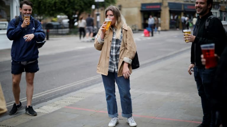 Des clients d'un pub à Londres boivent leur bière dans des verres en plastique à l'extérieur de l'établissement, en raison des restrictions contre le coronavirus alors en vigueur, le 5 juin 2020