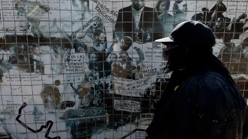Une femme devant un graffiti représentant les événements du 16 juin 1976 à Soweto