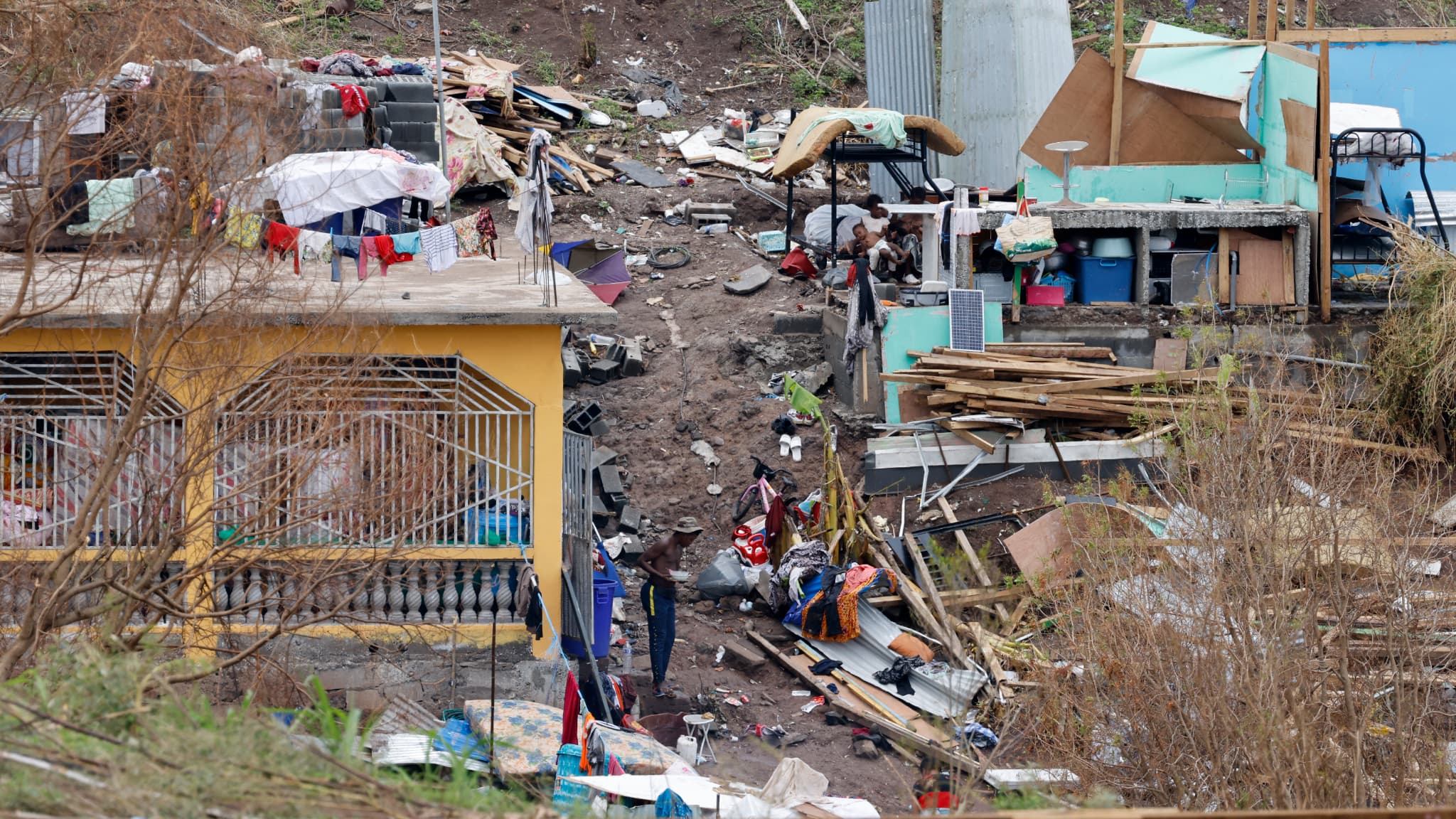 Des personnes cherchent des affaires et tentent de reconstruire au milieu des dégâts de l'habitat précaire du bidonville de l'agglomération kaweni de Mamoudzou, le 19 décembre 2024 Des personnes cherchent des affaires et tentent de reconstruire au milieu des dégâts de l'habitat précaire du bidonville de l'agglomération kaweni de Mamoudzou, le 19 décembre 2024