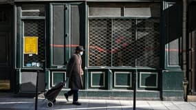 Un passant devant un magasin fermé --car ne faisant pas partie des commerces dits essentiels--, à Paris le 20 mars 2021 