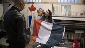 Une employée de "France drapeaux", qui confectionne des drapeaux à Gentilly (Val-de-Marne), montre un drapeau tricolore à un client.