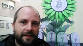Julien Guitton, fondateur et dirigeant de Condensat Technologies. Il s'est pris en photo devant le numéro 3 de la rue Legouvé à Paris, où une peinture de l'artiste Ludo montre le logo du Bitcoin au-dessus des tombes des monnaies traditionnelles, comme le dollar et l'euro.