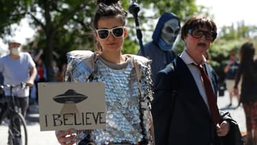 Une femme tient une pancarte "je crois" aux ovnis, lors d'une manifestation contre les tenants des théories du complot à Berlin le 30 mai 2020
